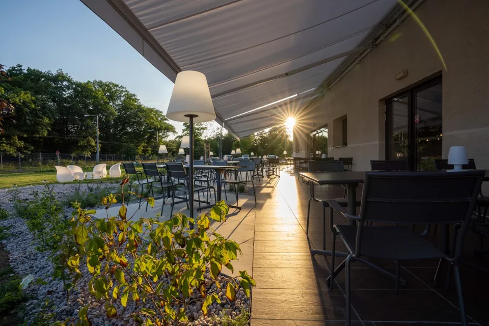 Venkovní terasa Hotelu Ibis Plzeň s&nbsp;posezením obklopená zelení